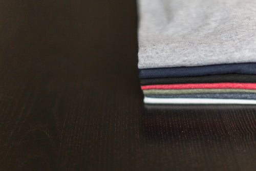 Sand colored linen cotton blend tees folded on wood table